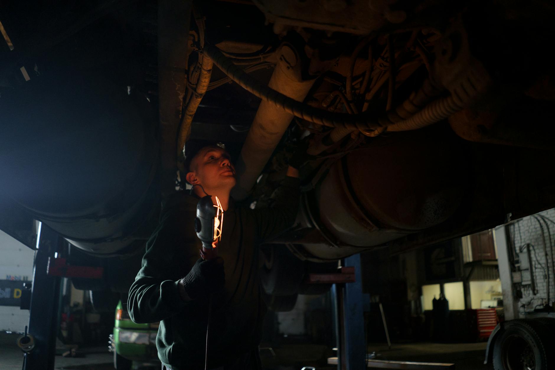 Mechanik z lampą kontroluje podwozie Forda w ciemnym warsztacie