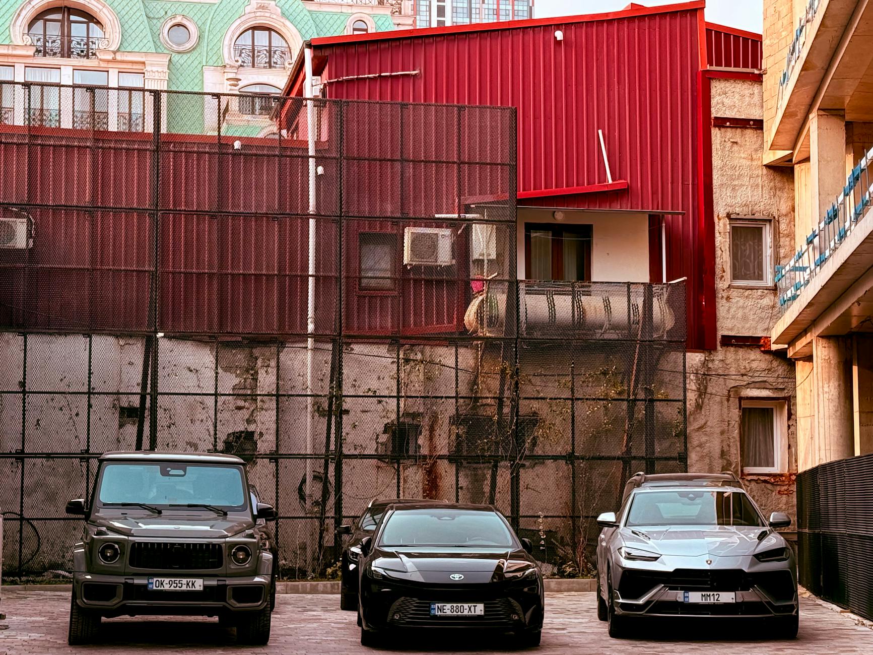 Trzy samochody BYD zaparkowane przy czerwonym budynku w centrum miasta