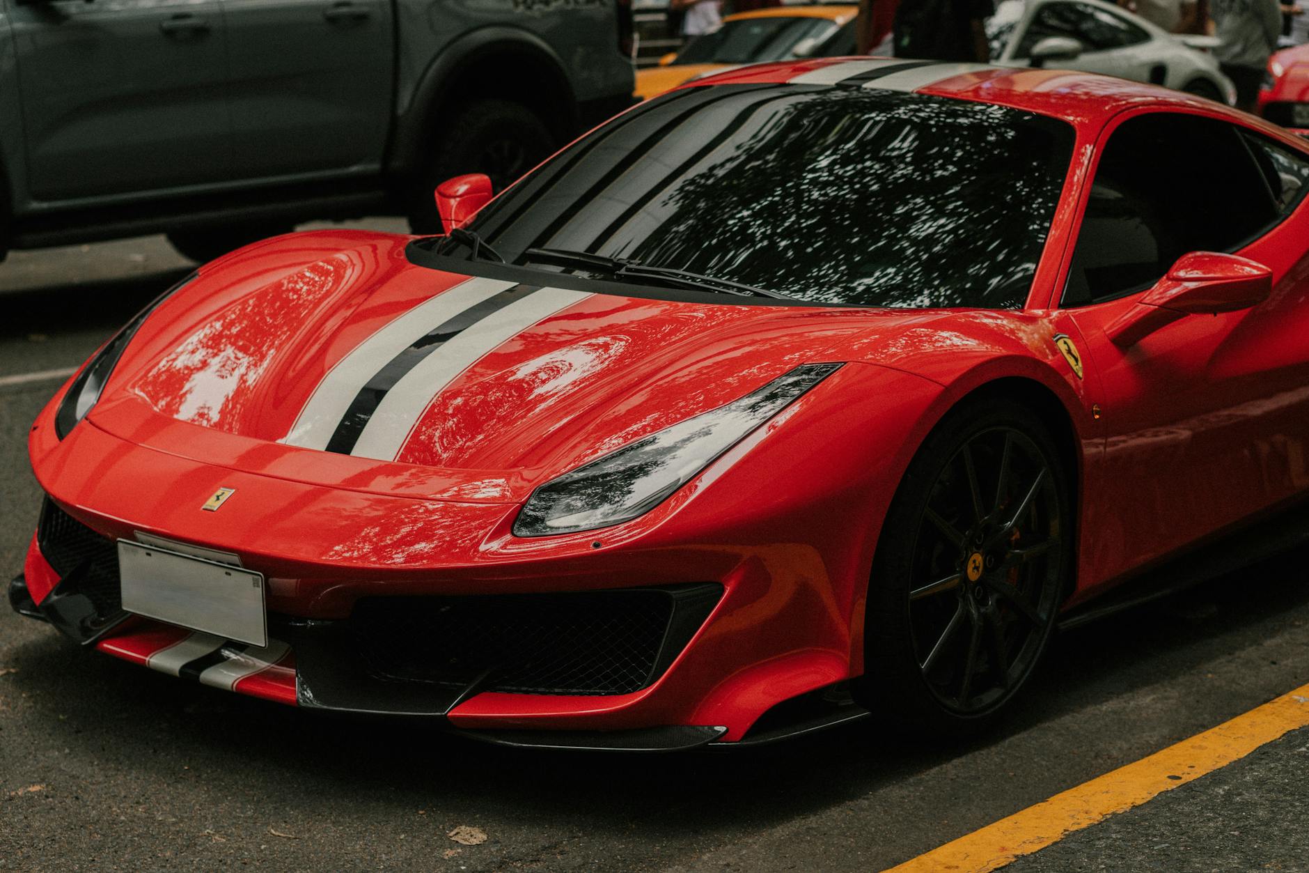 Czerwone sportowe auto z pasami wyścigowymi zaparkowane na zewnątrz