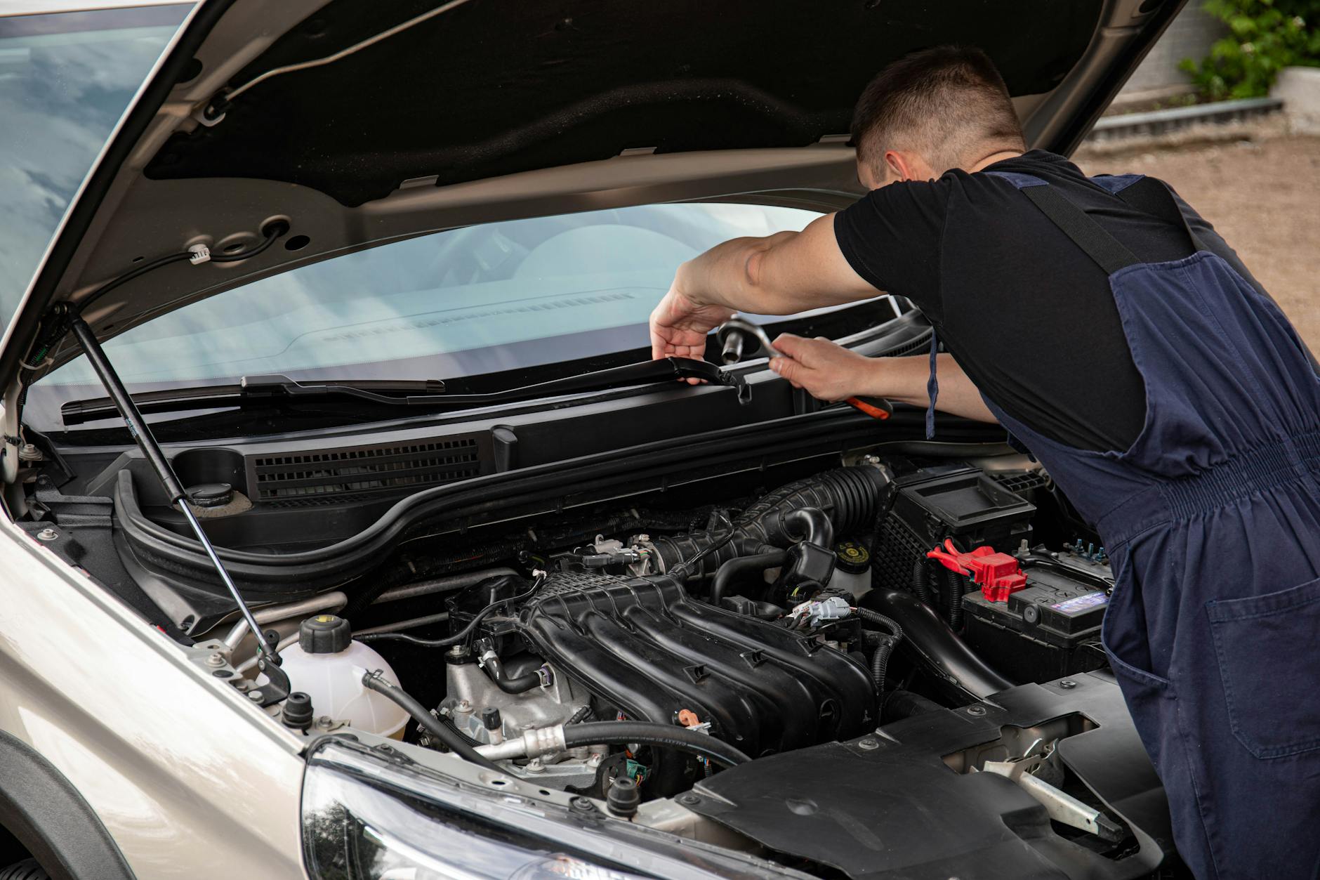 Zakup Geely z importu różnice w wyposażeniu ryzyka przy rejestracji oraz jak sprawdzić historię auta Mechanik naprawia silnik samochodu na zewnątrz w świetle dziennym