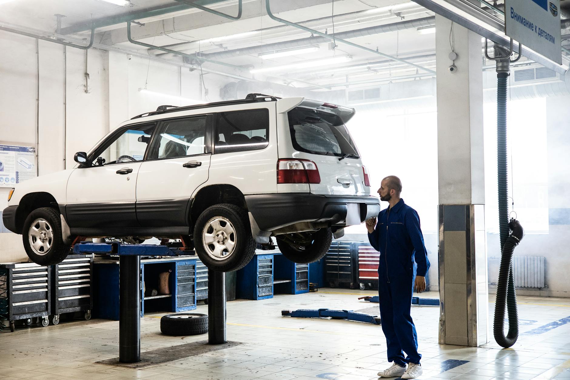 Mechanik sprawdza podniesionego SUV-a w nowoczesnym warsztacie