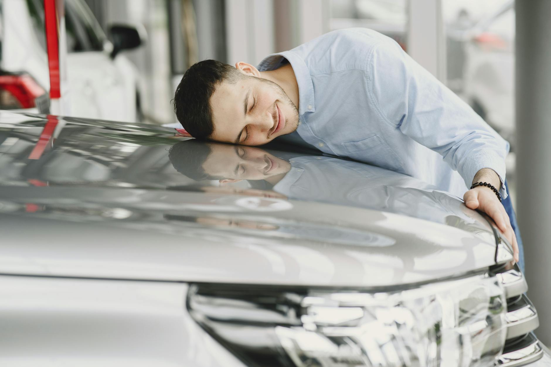 Mężczyzna obejmuje z radością nowy samochód w salonie Peugeot
