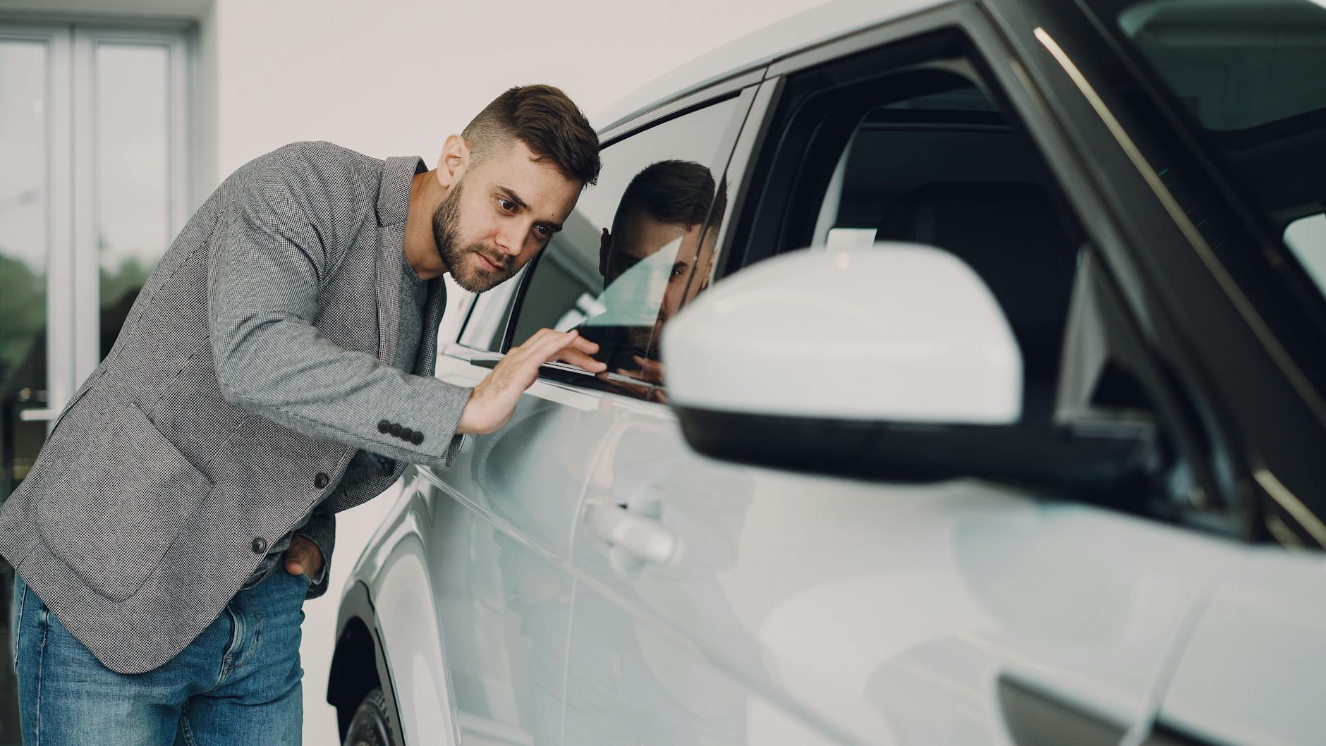 Mężczyzna ogląda nowego białego Peugeota 308 w salonie samochodowym