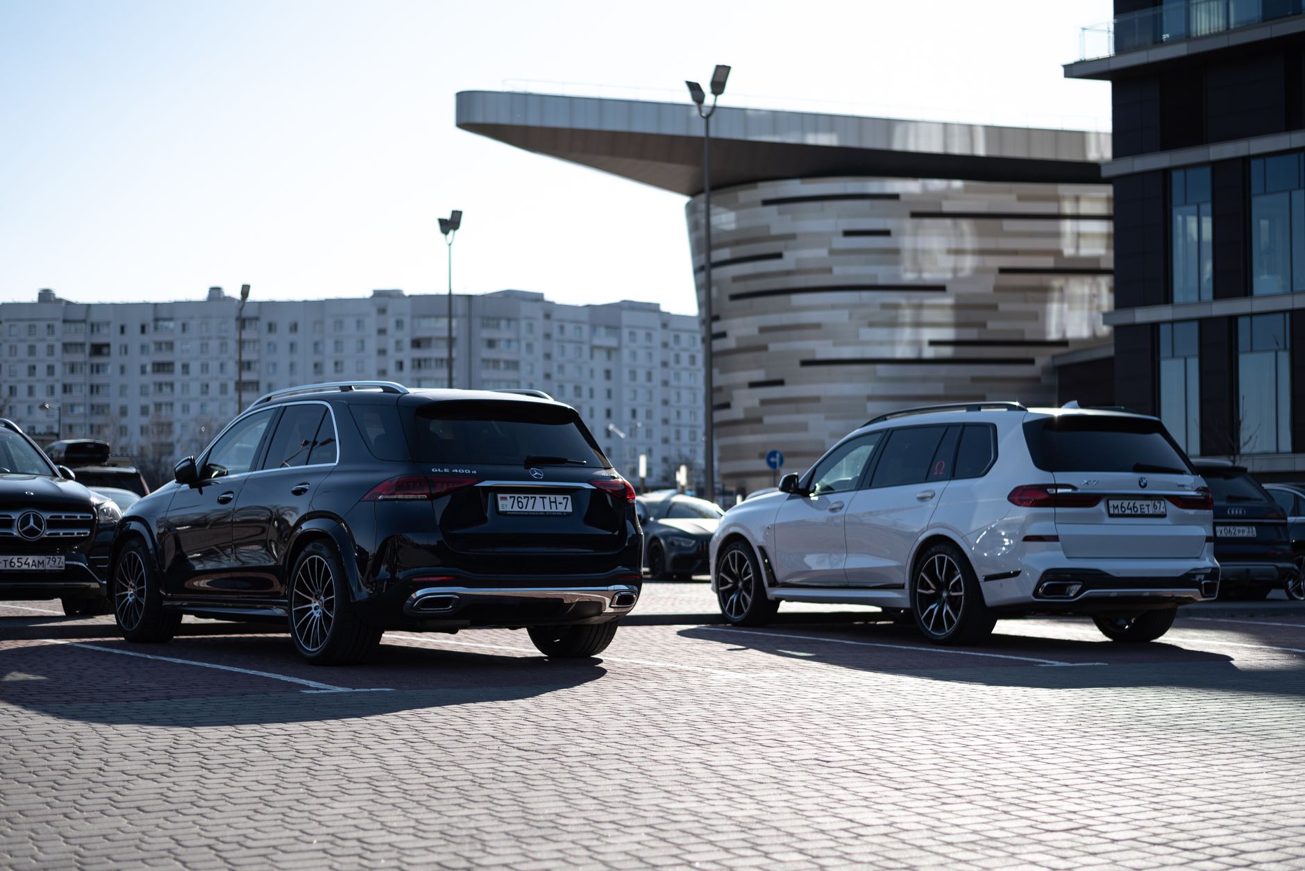 Dwa luksusowe SUV-y Bentley zaparkowane wśród nowoczesnych biurowców