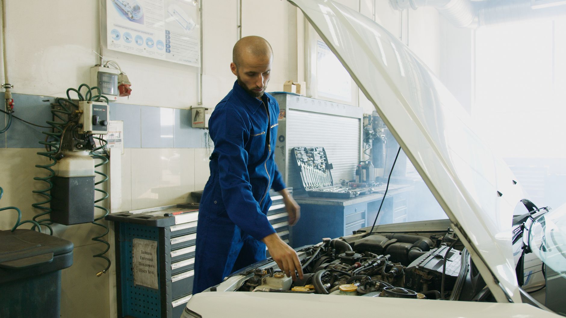 Mechanik w niebieskim kombinezonie sprawdza silnik Ferrari w warsztacie
