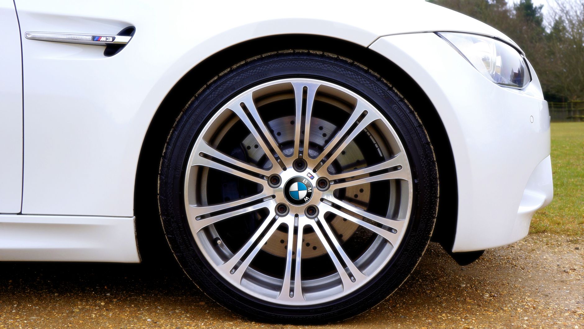 Zbliżenie na aluminiową felgę BMW M3 i fragment błotnika