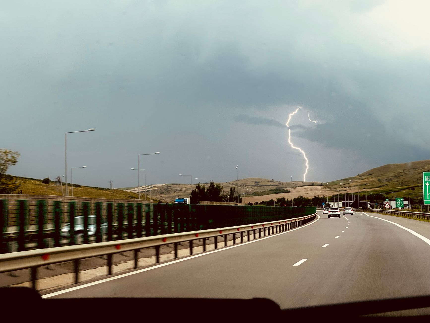 Jak zaplanować pierwszą długą podróż Teslą praktyczny poradnik krok po kroku Burza z piorunami nad autostradą widzianą z jadącego samochodu Tesli